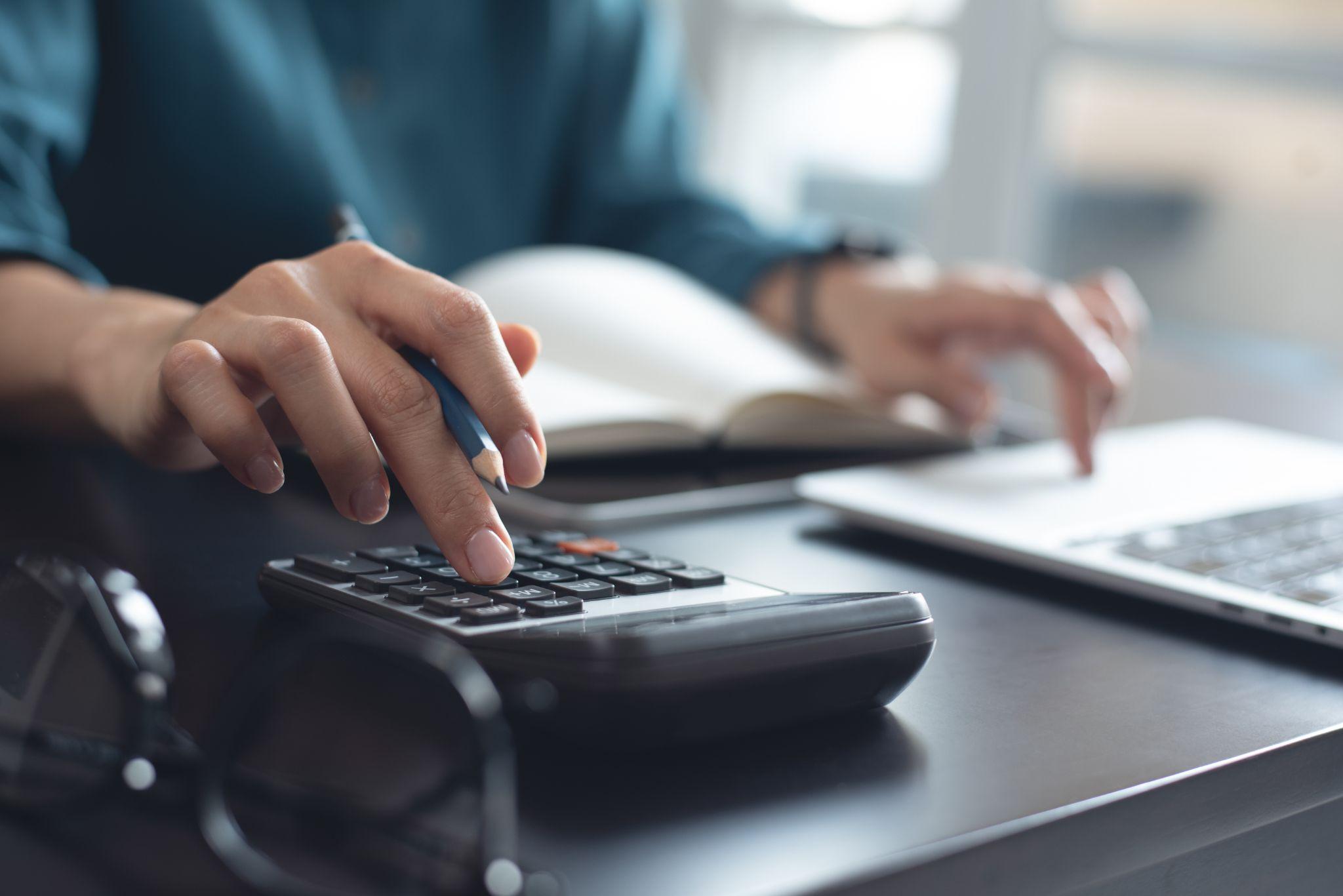 Calcolatrice e documenti finanziari su una scrivania: calcolo del budget di lancio e ripartizione delle spese per una boutique di moda (acquisti B2B).