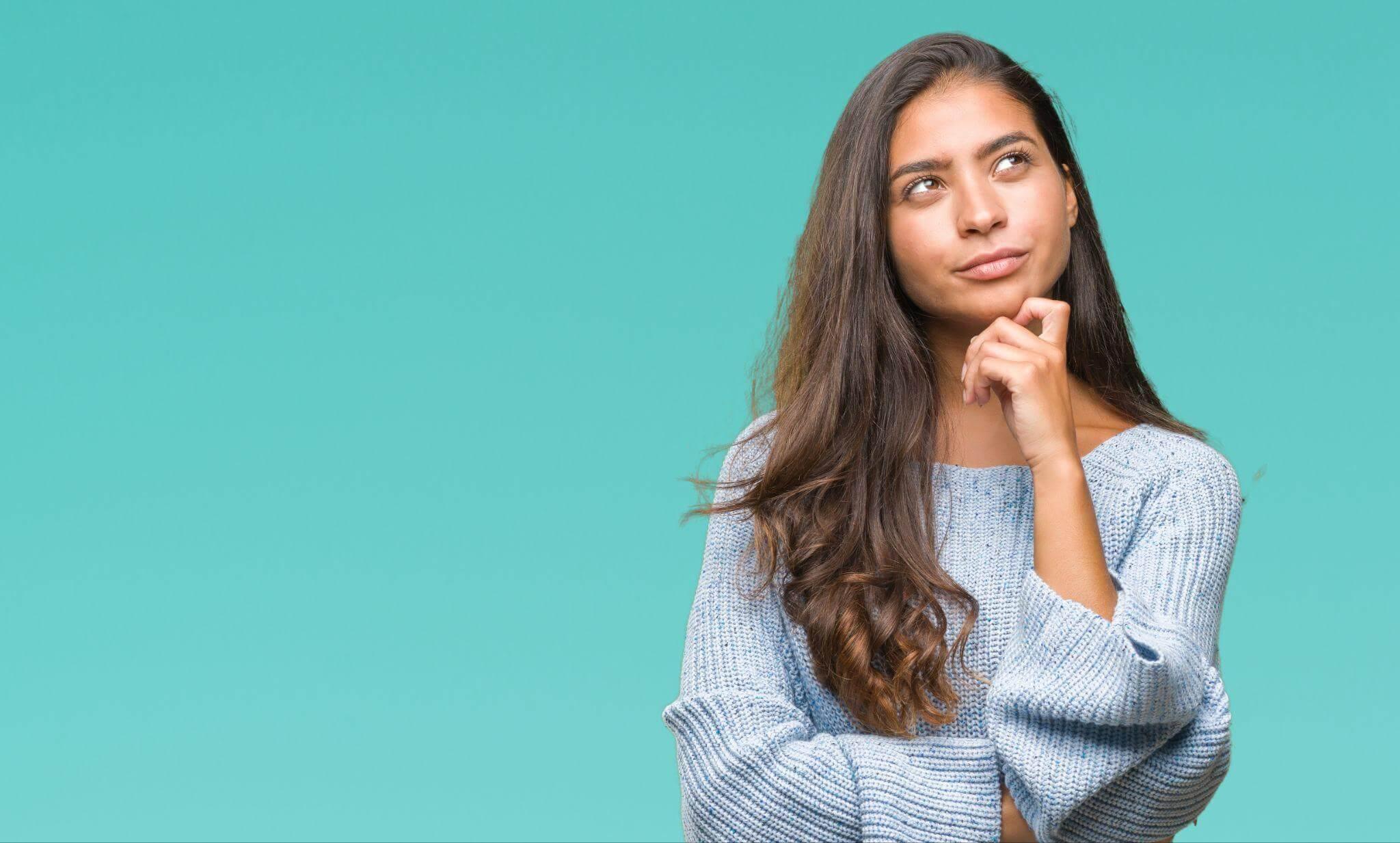 Femme posant sa main gauche sur son menton et levant les yeux au ciel. Elle réfléchit à comment éviter les investissements lourds sans validation.