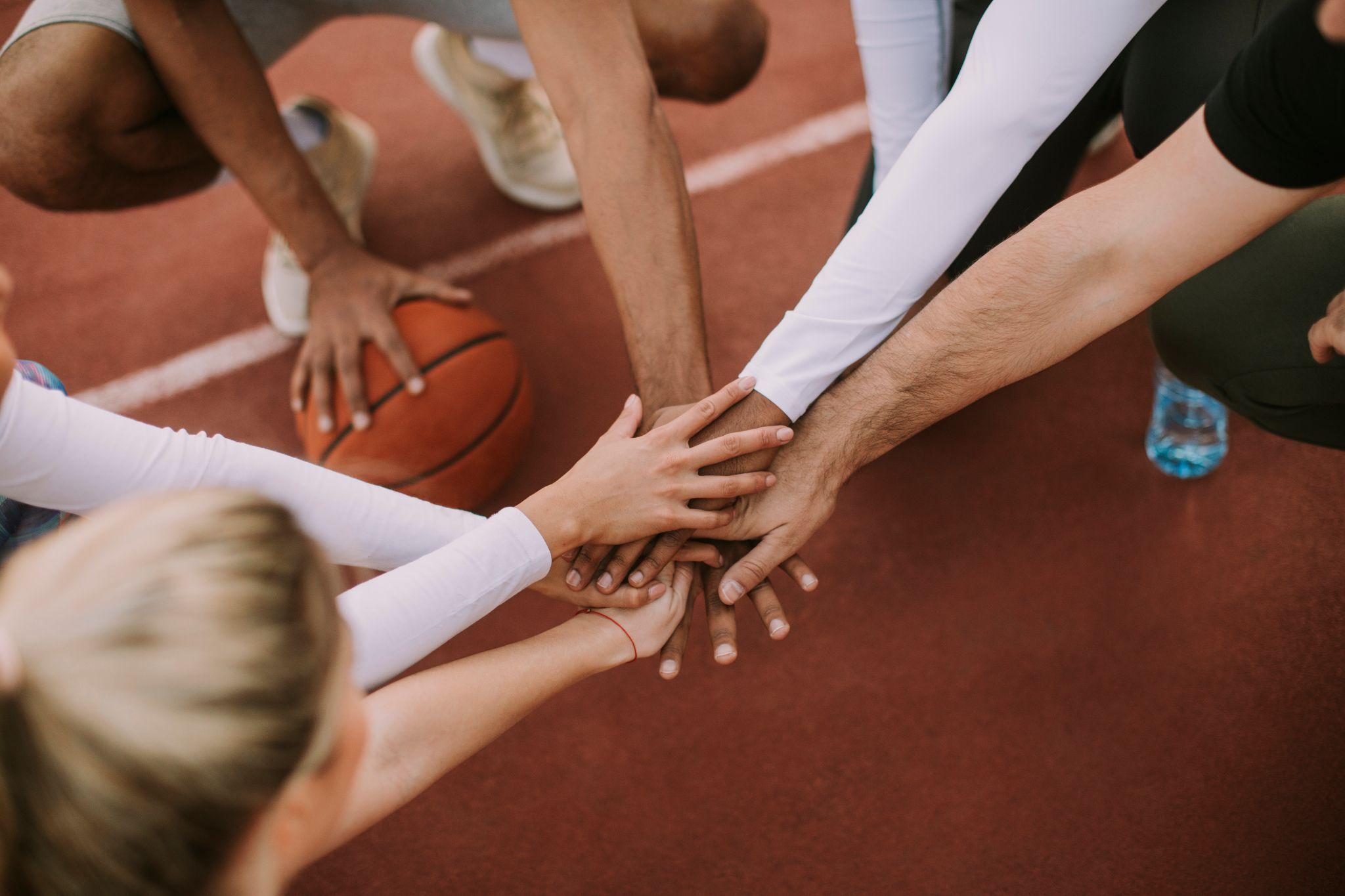 Groupe de personne en pleine activité sportive. Un des joueur à la main sur un ballon de basket.