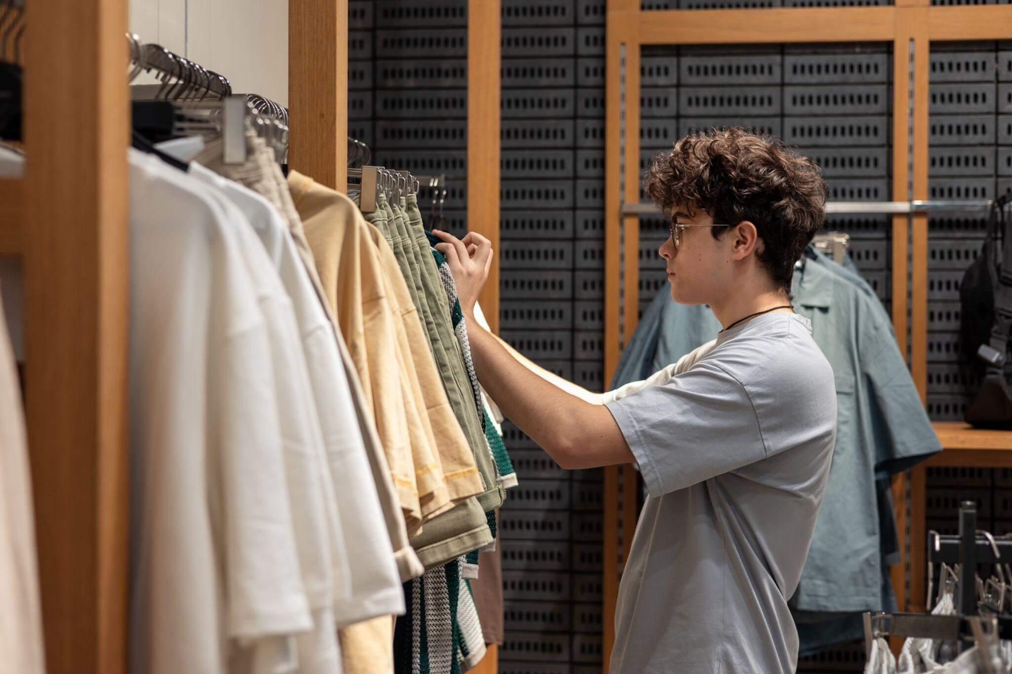Joven gestionando existencias en una tienda de ropa de moda.