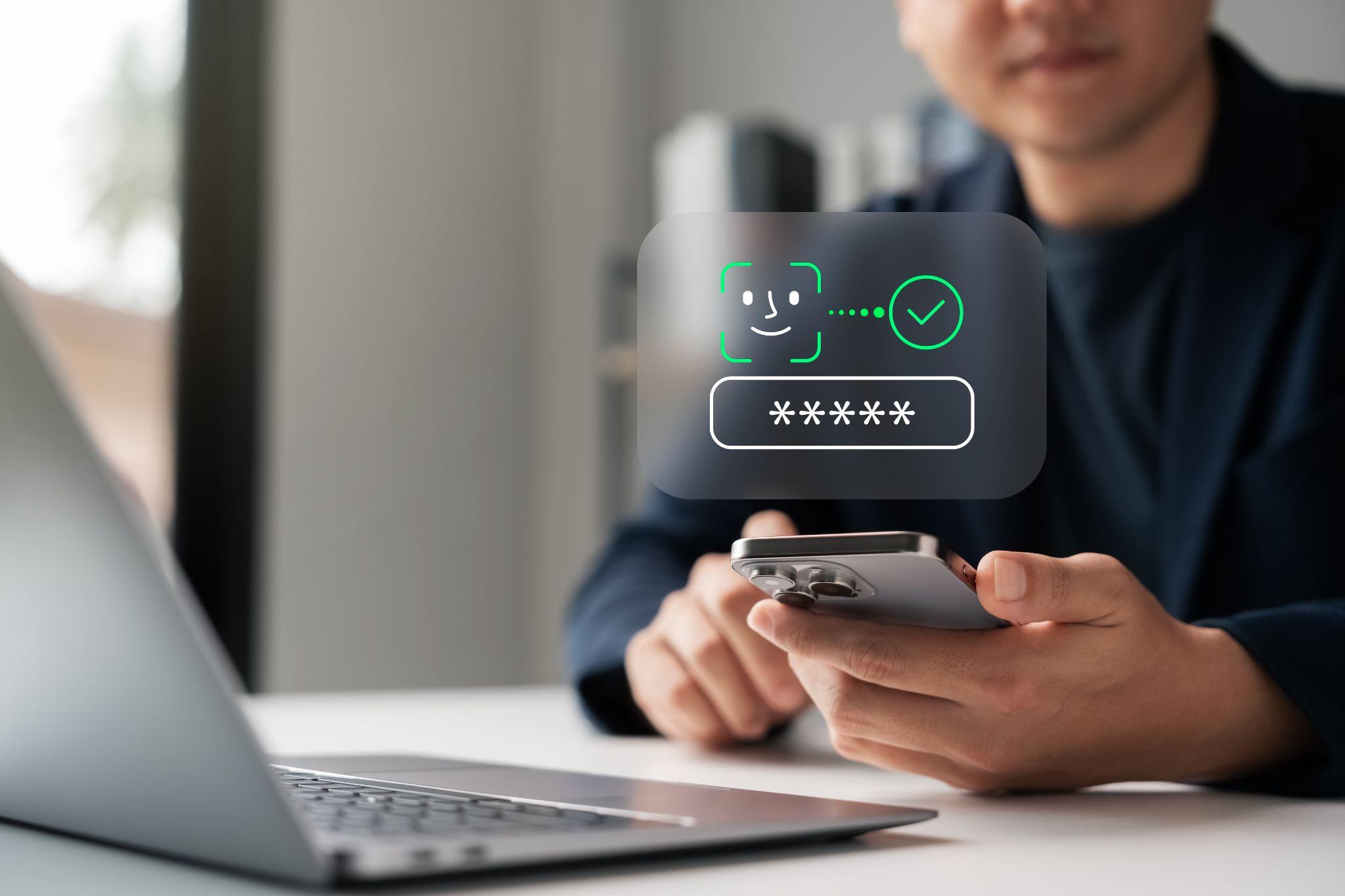Mano che tiene uno smartphone davanti a un computer portatile con verifica del fornitore.