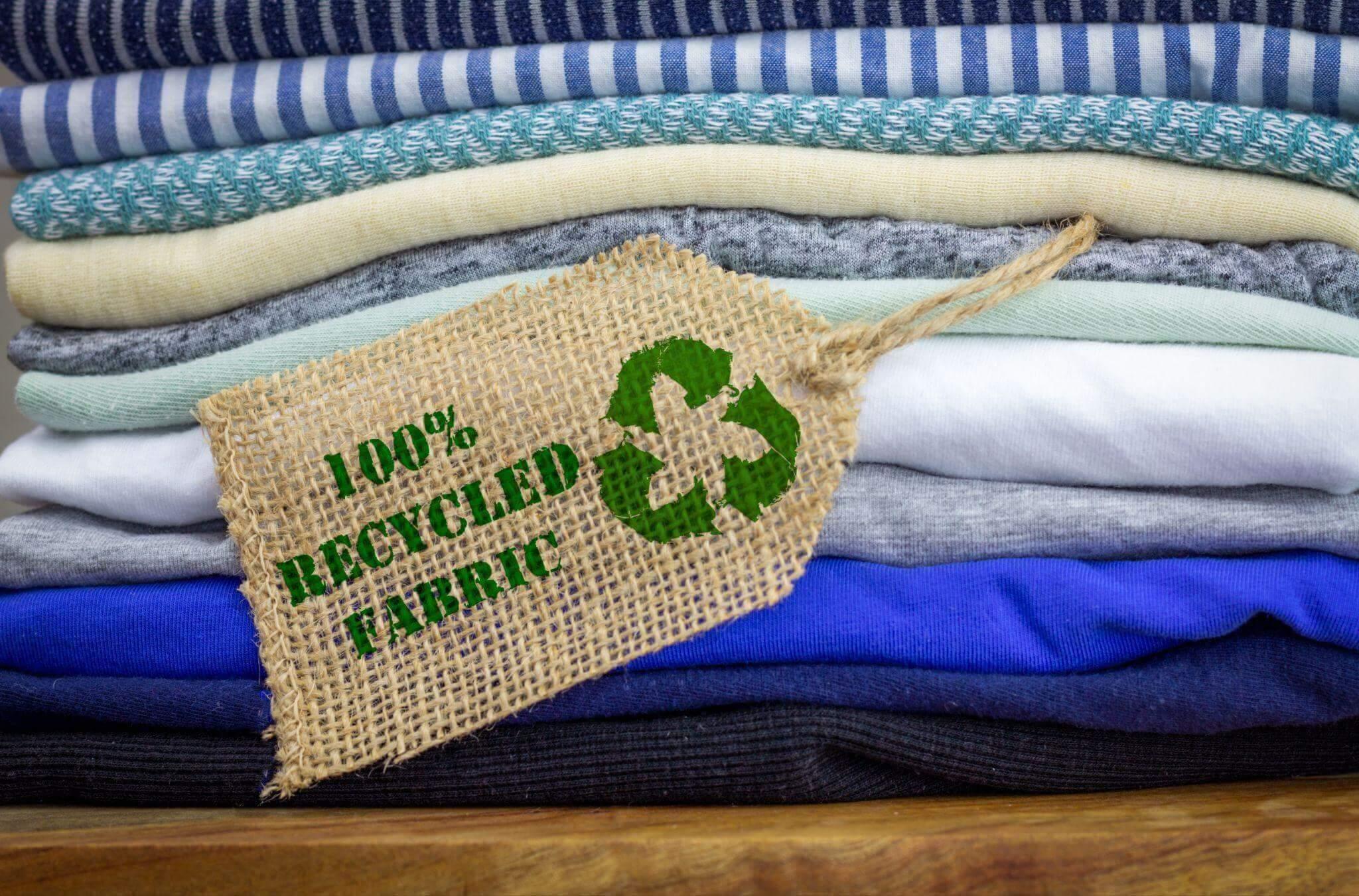Pilha de roupas de cores diferentes, certificadas e 100% recicladas.