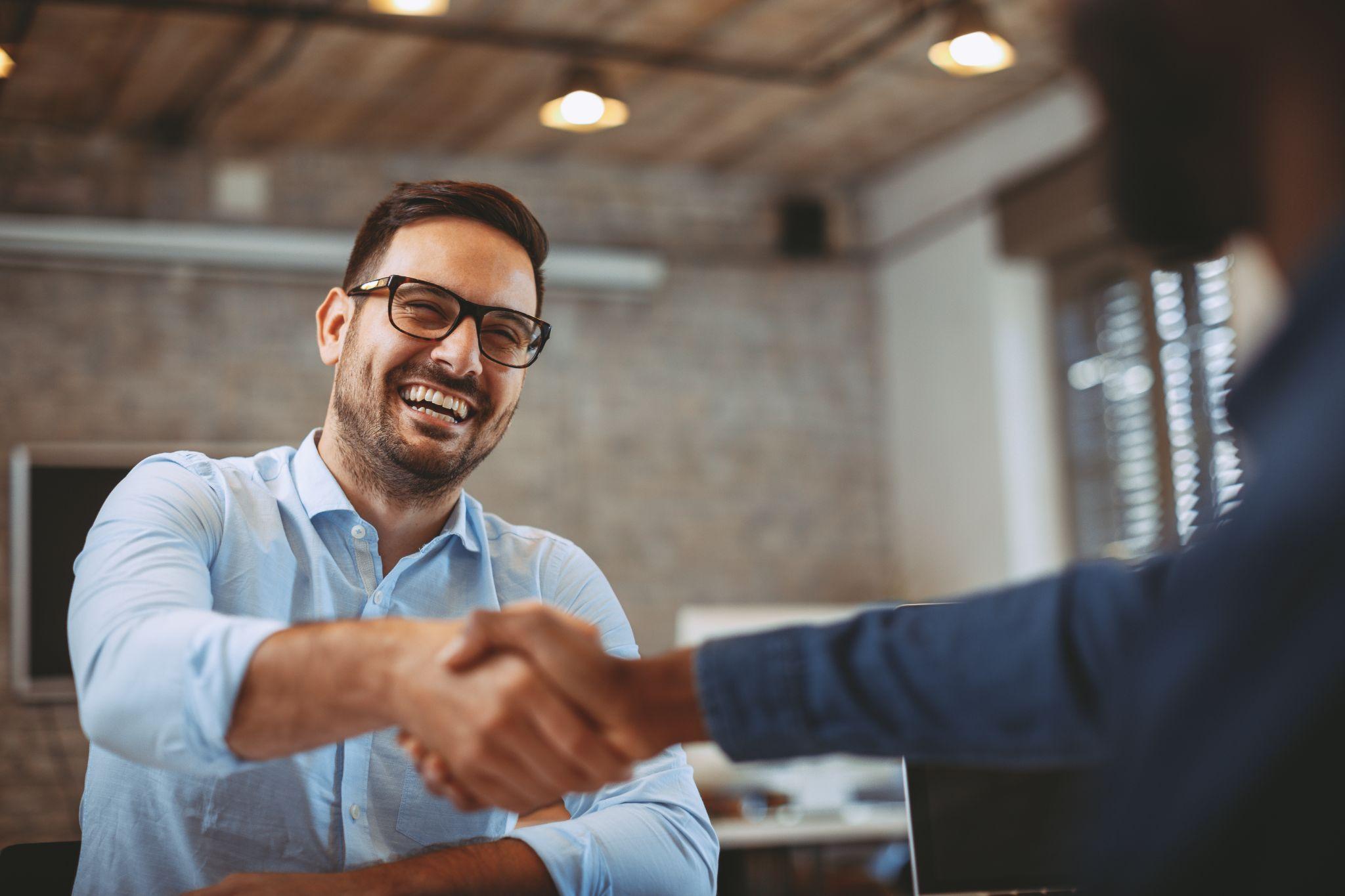 Poignée de main entre partenaires, sourire — accord de collaboration avec un fournisseur.