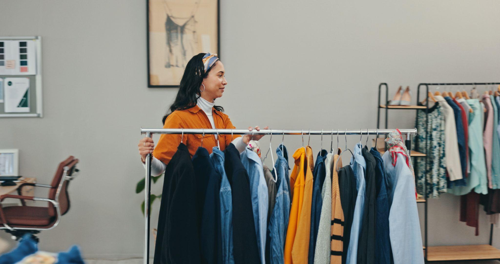 Responsable boutique ajustant des vêtements sur un portant — contrôle qualité et sélection de collections chez le grossiste.