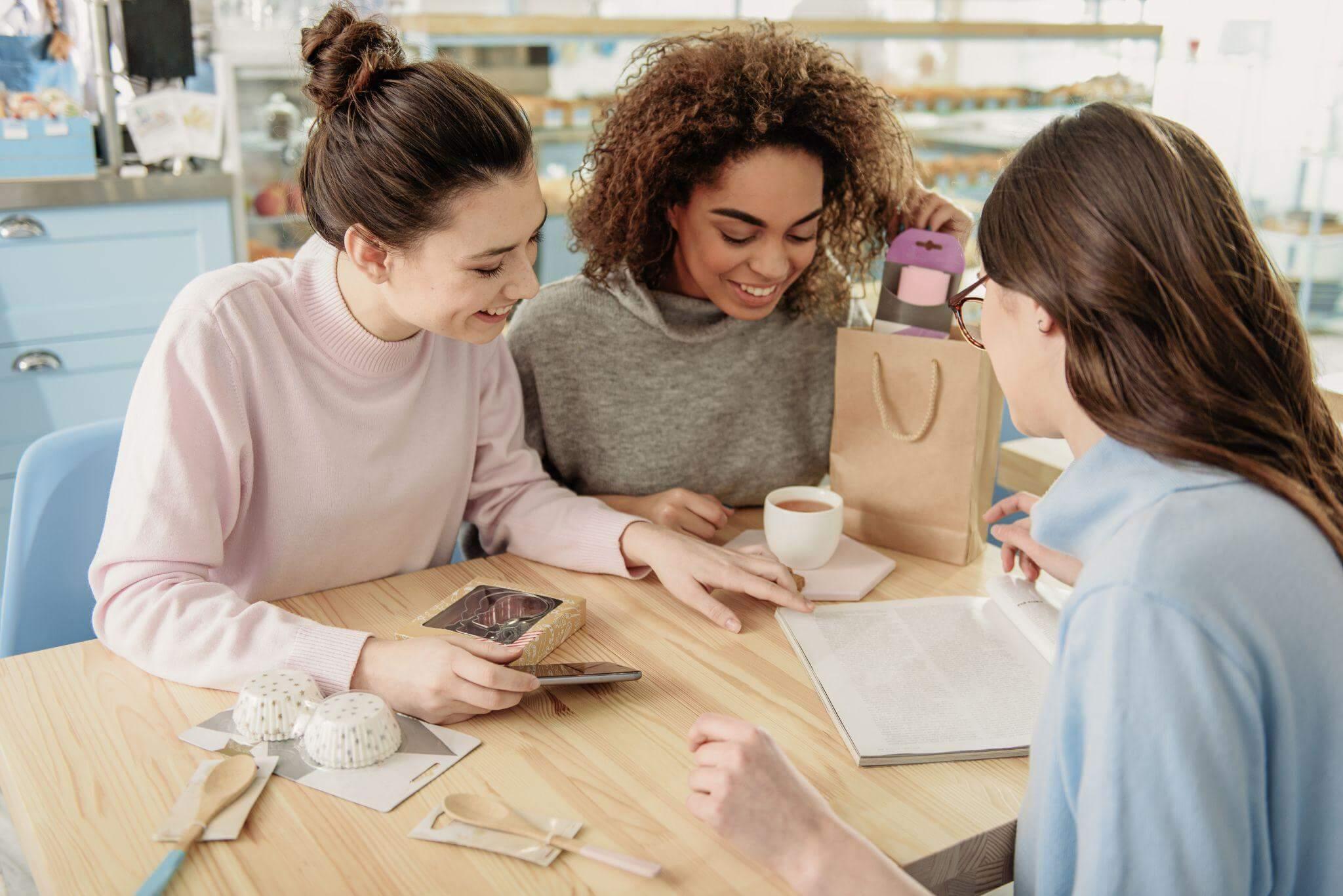 Trois femmes sont réunies autour d'une table. Elles préparent leurs projet.
